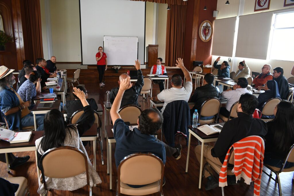 Personas levantando la mano para tomar decisión en la Asamblea de Cáritas Ecuador 2025